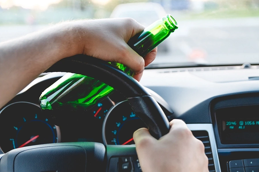 Person holding beer bottle while driving